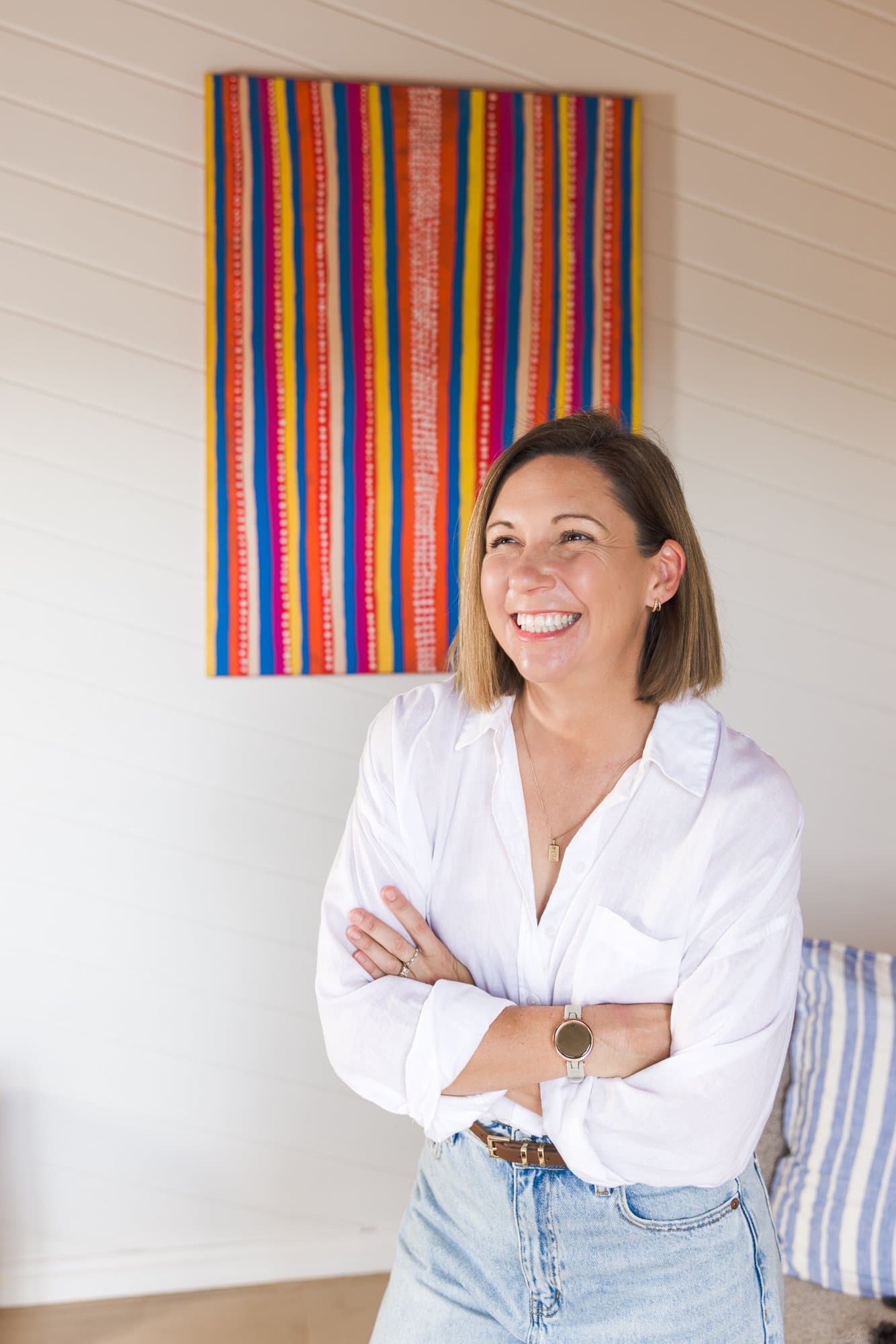 Steph laughing with her arms crossed in front of a bright striped painting