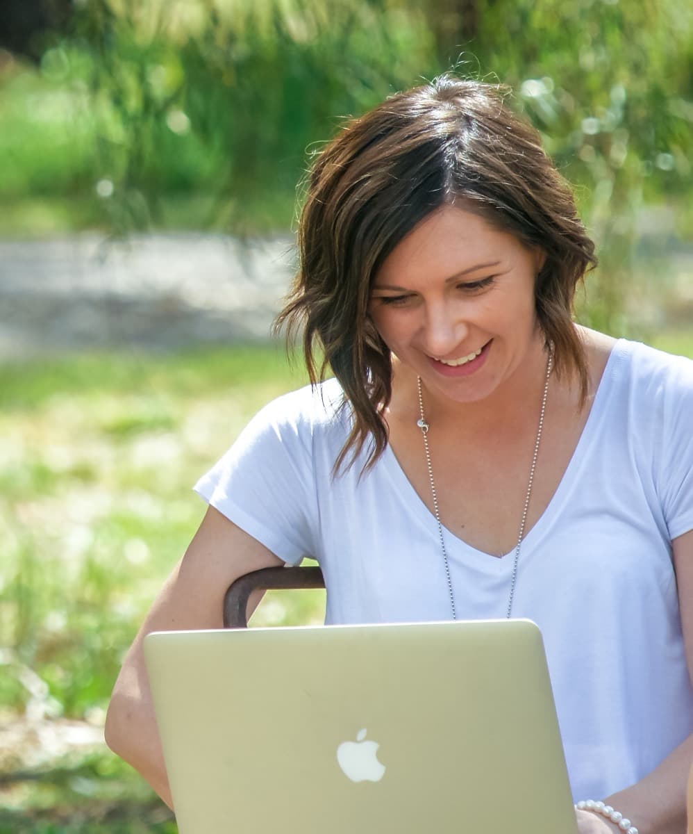 Steph working on a laptop outdoors under a willow tree