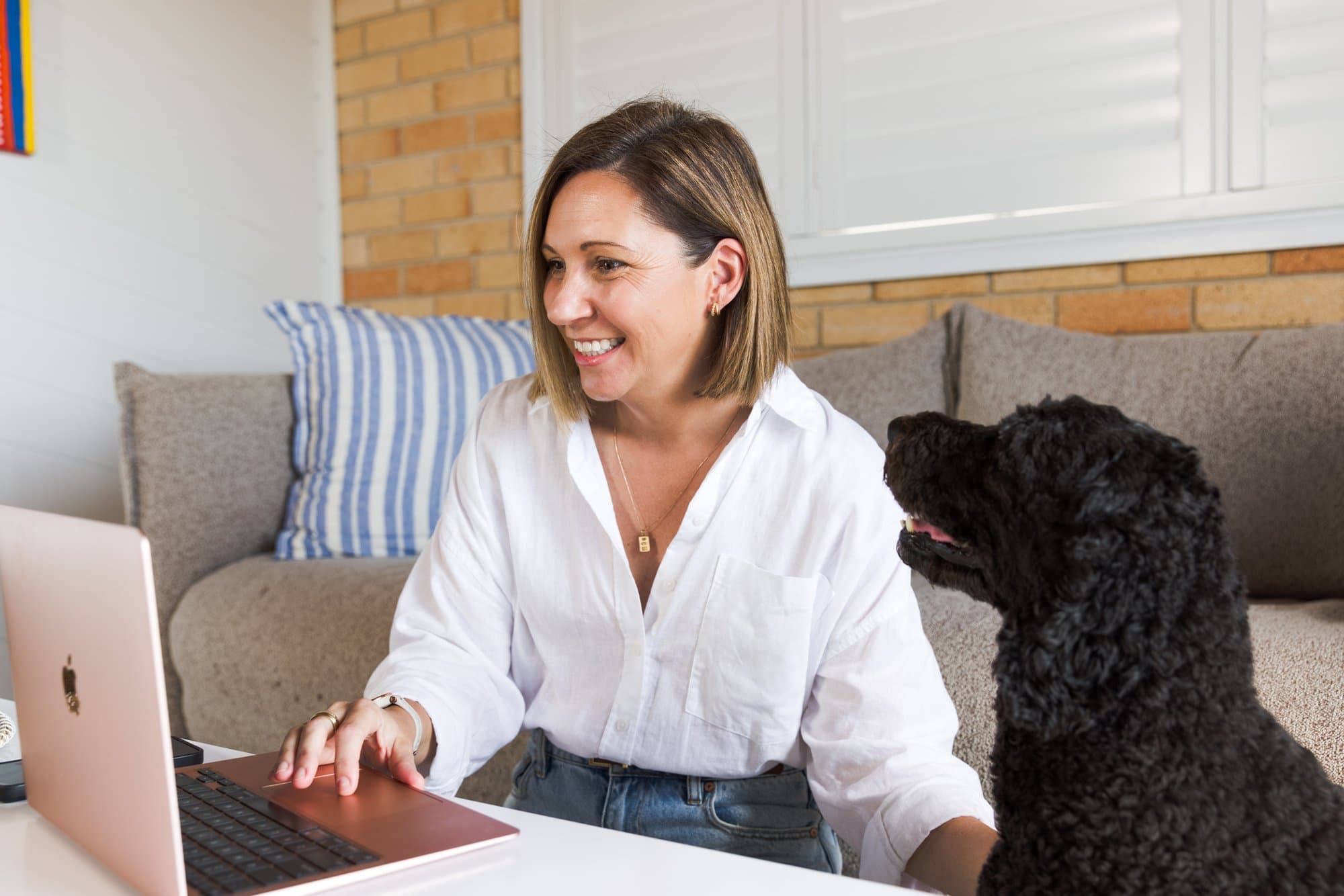 Steph working on her laptop while her dog looks on