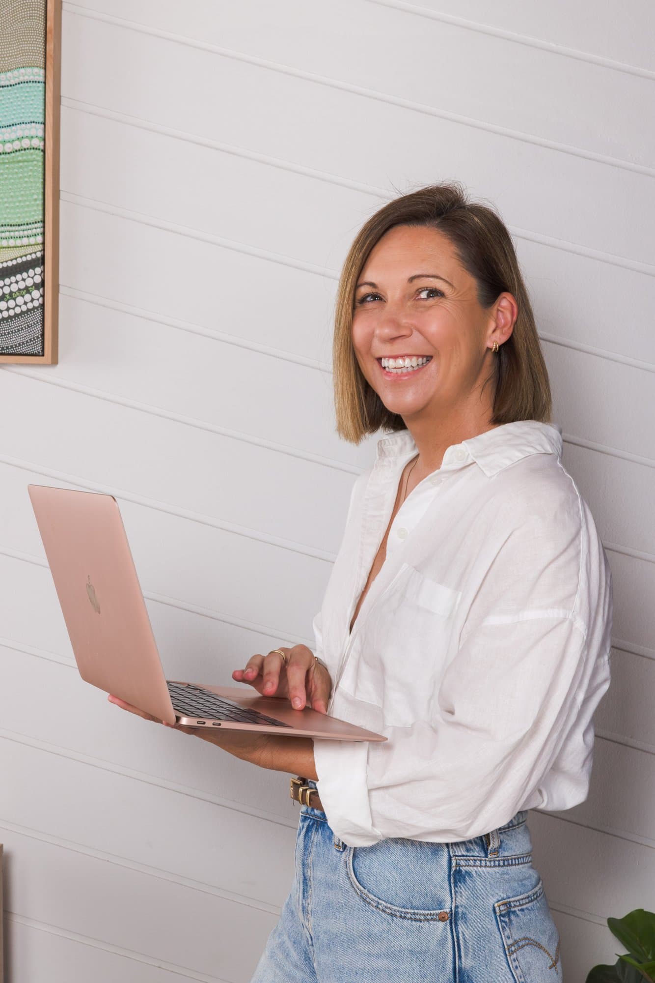 Steph smiling while typing on the laptop held in her hands