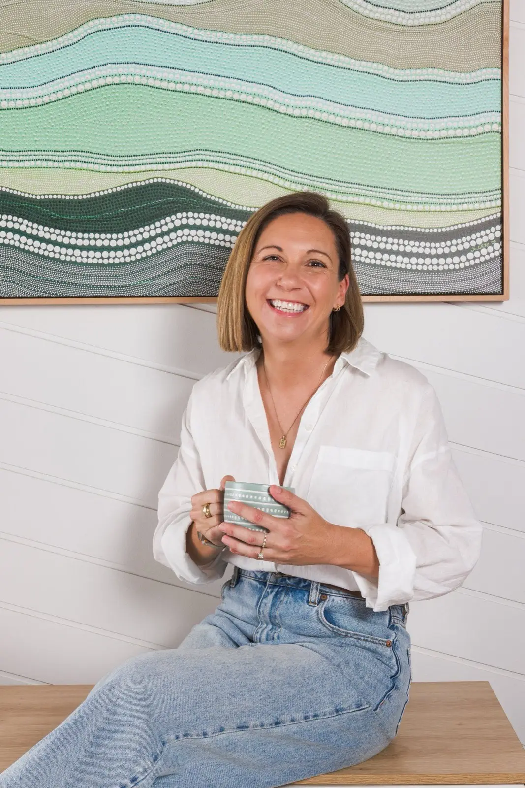 Steph looking at the camera while seated with her mug