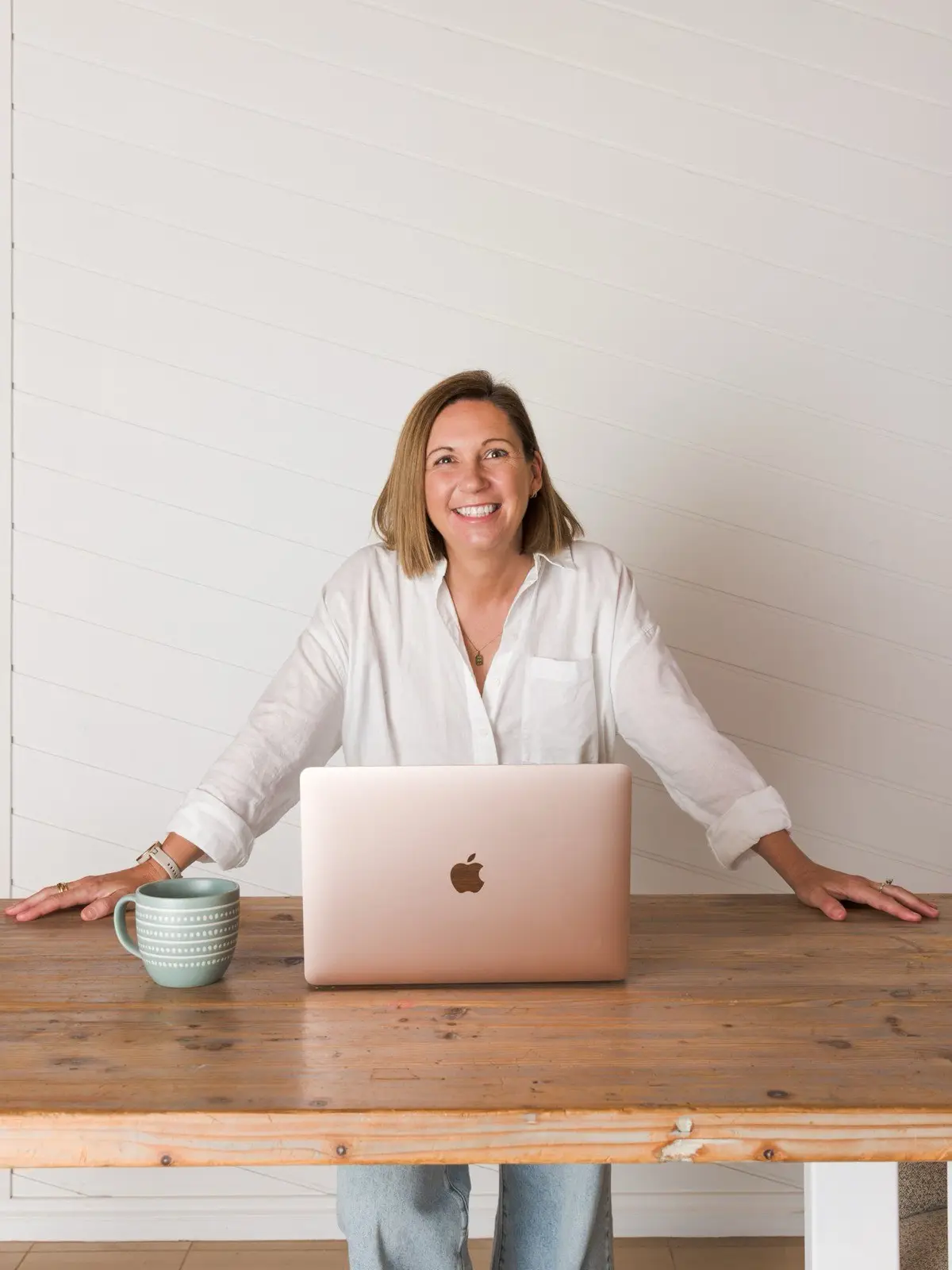 Steph smiling behind her laptop at a timber table